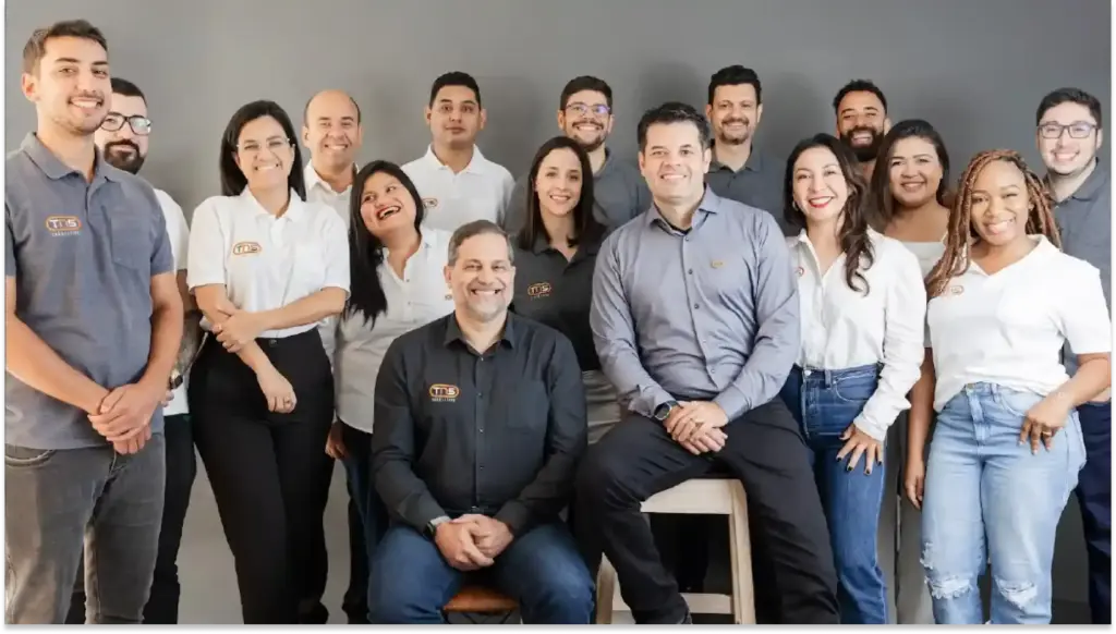 Grupo de profissionais da Tennessine sorrindo em ambiente de escritório, representando equipe de trabalho unida e colaborativa.