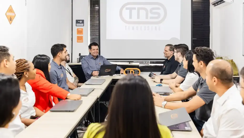Grupo de profissionais da Tennessine sorrindo em ambiente de escritório, representando equipe de trabalho unida e colaborativa.