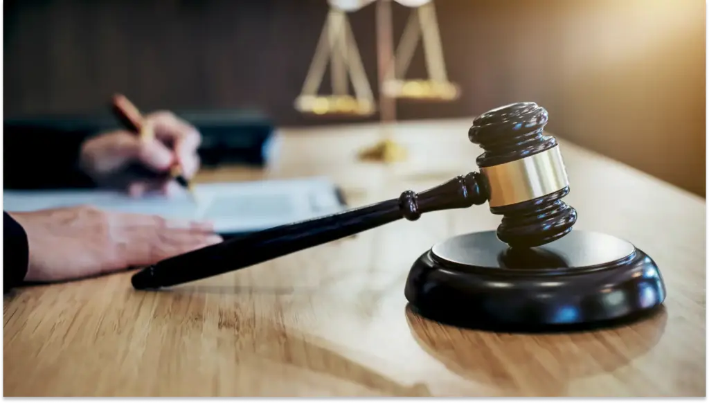 Imagem de um martelo de juiz em uma mesa de tribunal, simbolizando ações trabalhistas, com uma balança ao fundo. Perfeita para artigos sobre leis, justiça e advocacia.