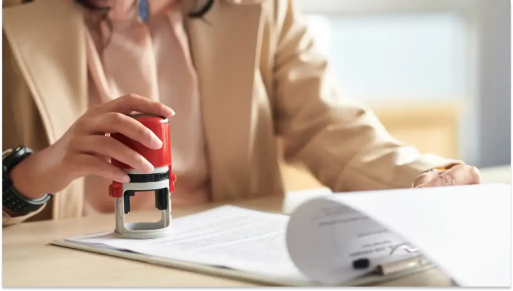 Pessoa usando carimbo para cancelar registros sindicais inativos importantes, destacando a importância da assinatura em contratos e papéis oficiais.