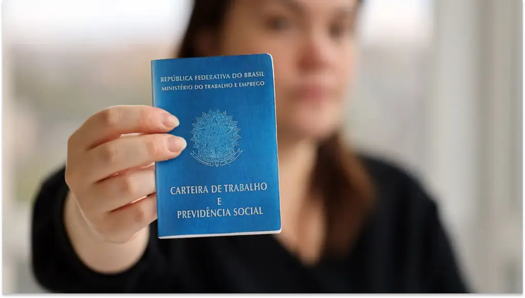 Mulher segurando uma carteira de trabalho padrão do regime celetista, que é o principal para trabalhadores no Brasil sob a legislação trabalhista vigente.