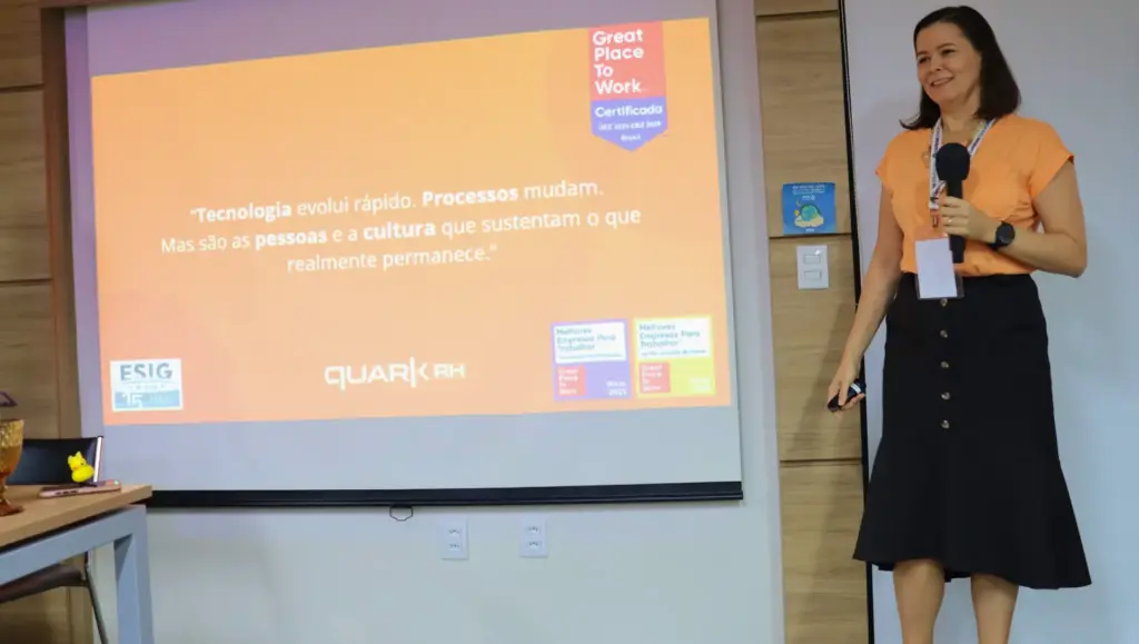 Participante palestrando em um workshop com apresentação projetada sobre Gestão de Pessoas de Alta Performance, com mensagem “Tecnologia evolui rápido” e certificados Great Place to Work ao fundo.
