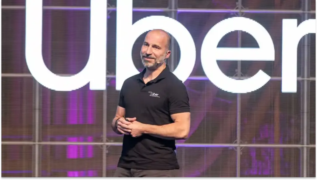 Imagem do executivo da Uber em palco, falando durante apresentação com o logotipo da empresa ao fundo, em contexto de anúncio de reestruturação e redução do time de RH e recrutamento em 23%.