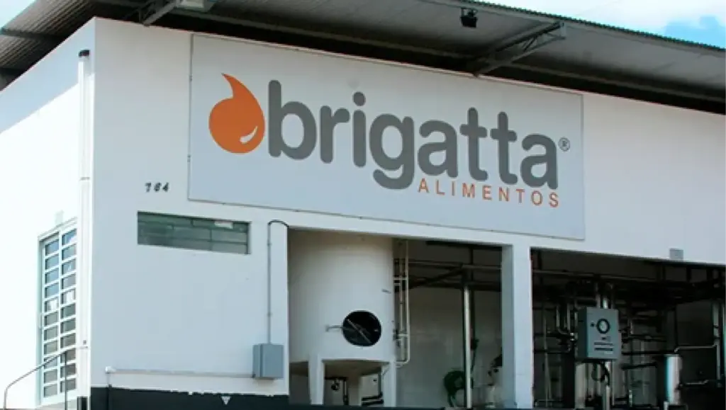 Fachada de uma unidade com a marca brigatta ALIMENTOS em destaque, com entrada e estrutura industrial ao fundo.