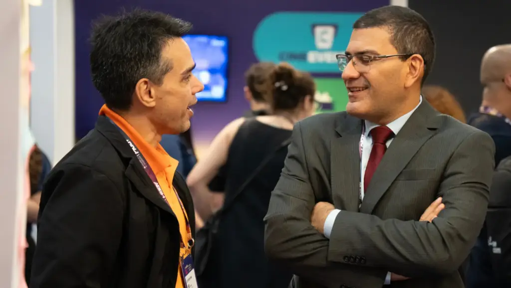 Encontro e networking no estande de evento corporativo durante a CONARH 2026, com Gleydson Lima e outro participante conversando e trocando cumprimentos em um ambiente de feira.