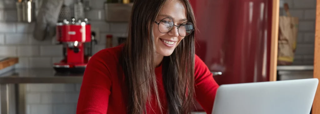 Mulher sentada em uma mesa usando um laptop, sorrindo. O texto ao lado pergunta sobre o Departamento Pessoal, suas funções e importância.