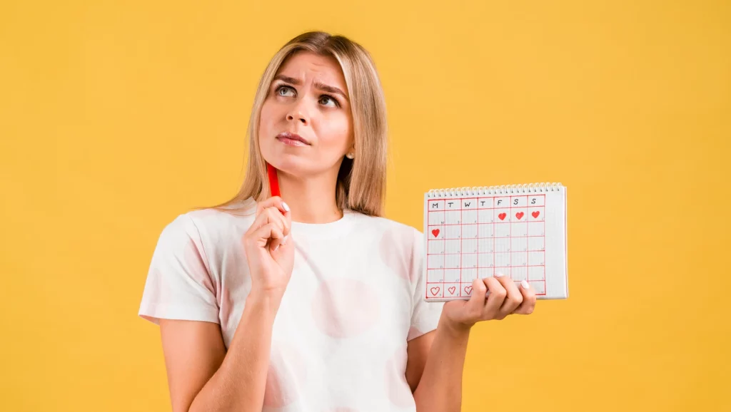 Mulher com expressão pensativa segurando um calendário e caneta, refletindo sobre compromissos ou metas da semana e trabalho em feriados com fundo amarelo.