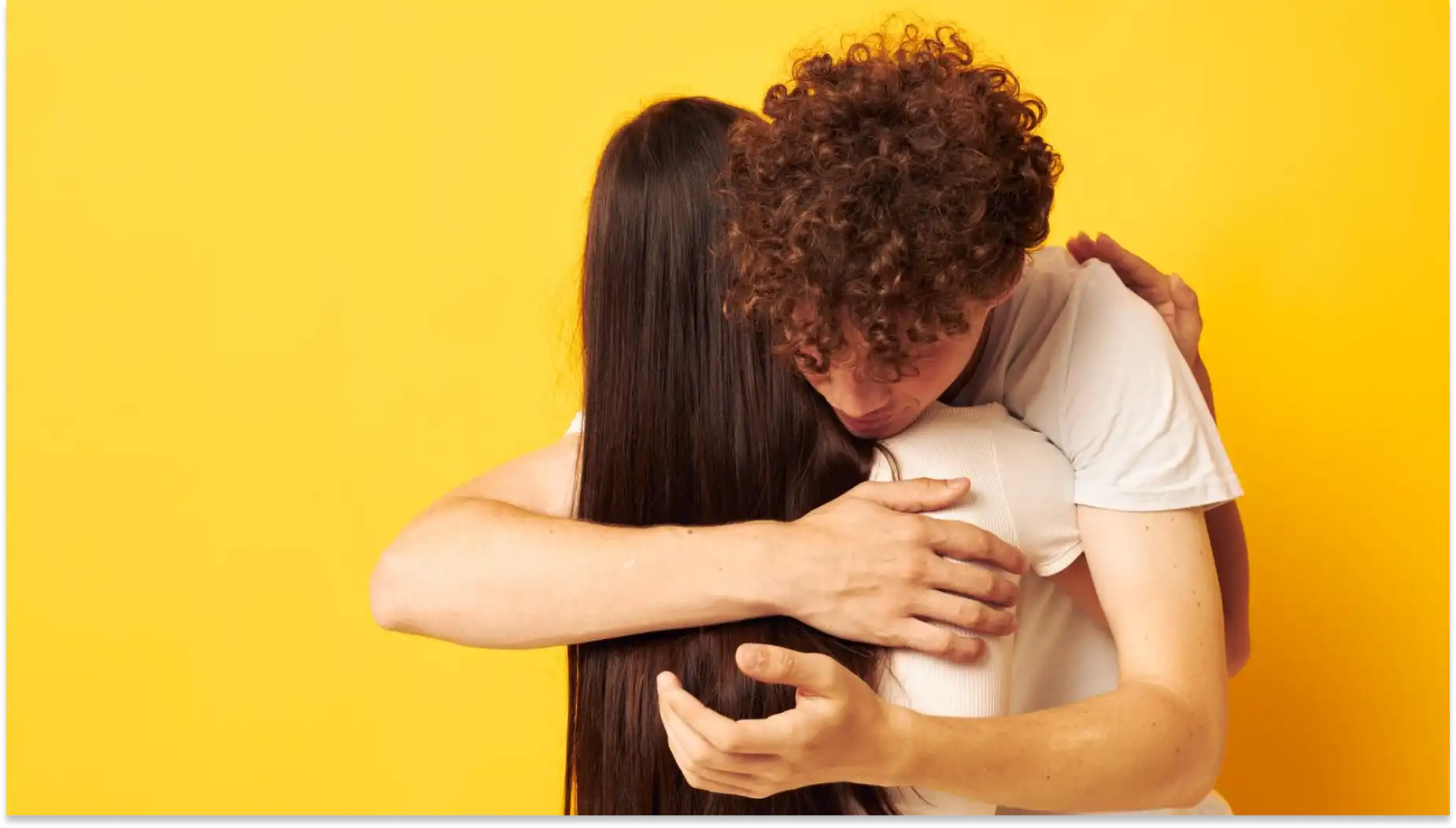 Imagem de um casal se abraçando com emoção, símbolo de amor e conexão emocional, contra fundo amarelo vibrante. Representa Campanha Setembro Amarelo.