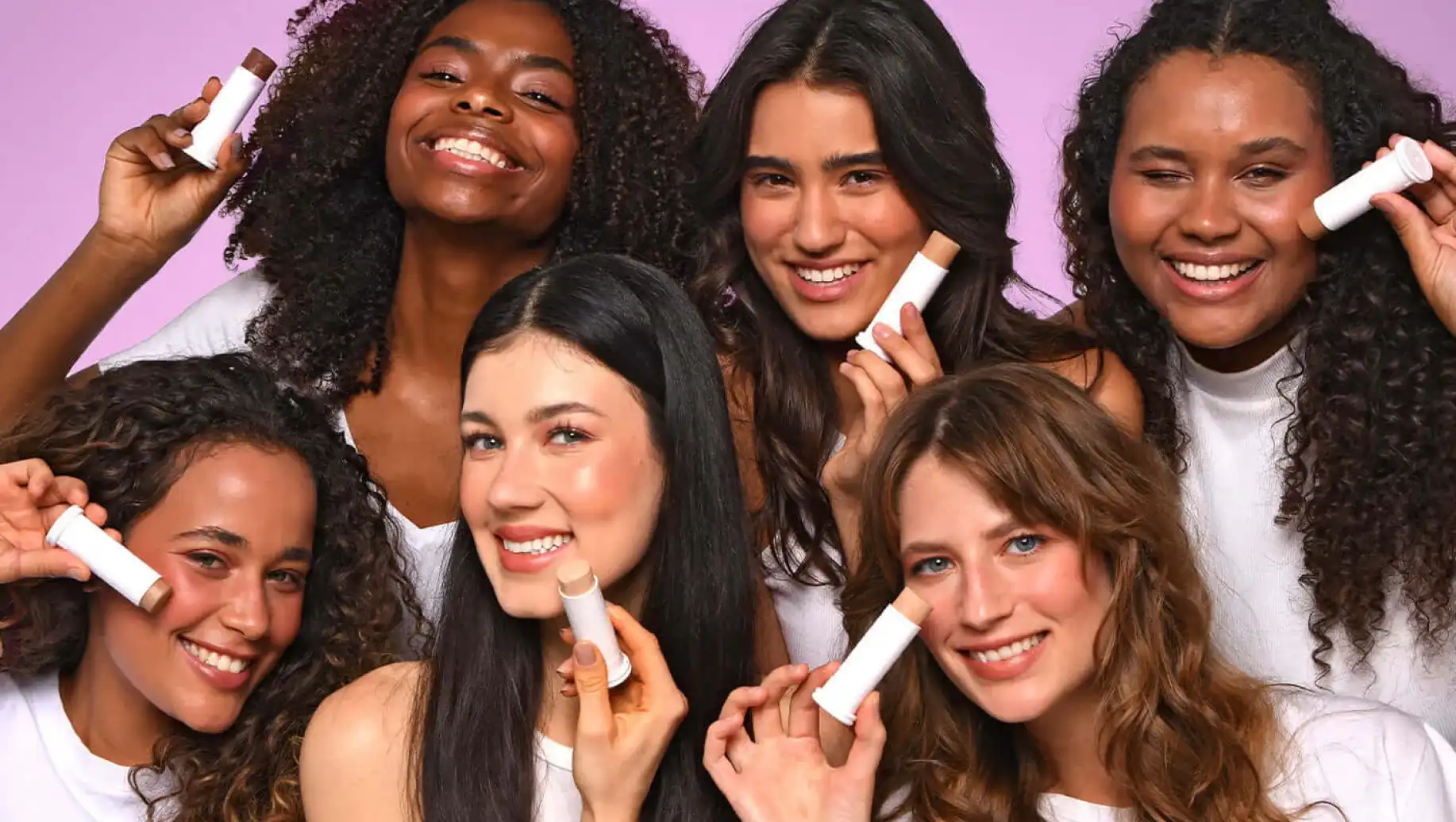 Grupo de jovens Ollie sorrindo com produtos de beleza, promovendo cuidados com a pele e autoestima. Mulheres de diferentes etnias usando protetor solar Ollie.
