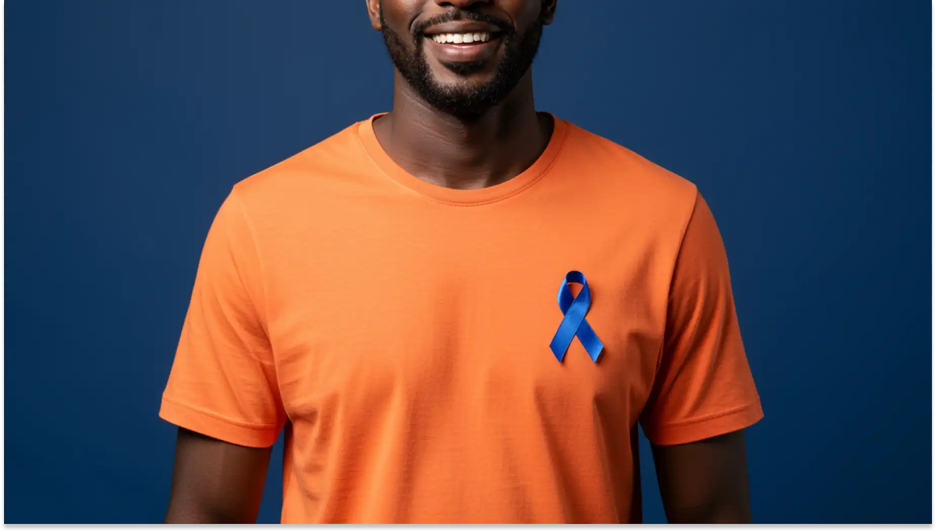 Homem sorridente usando camiseta laranja com fita azul de conscientização ao lado de parede azul, promovendo consciêntização para o novembro azul.