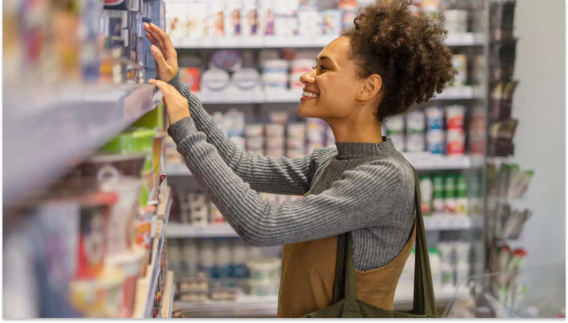 Mulher sorridente fazendo compras, de acordo com as novas regras para vales, em uma loja, pegando itens na prateleira com pelo menos 150 caracteres, enfatizando a experiência de compra.