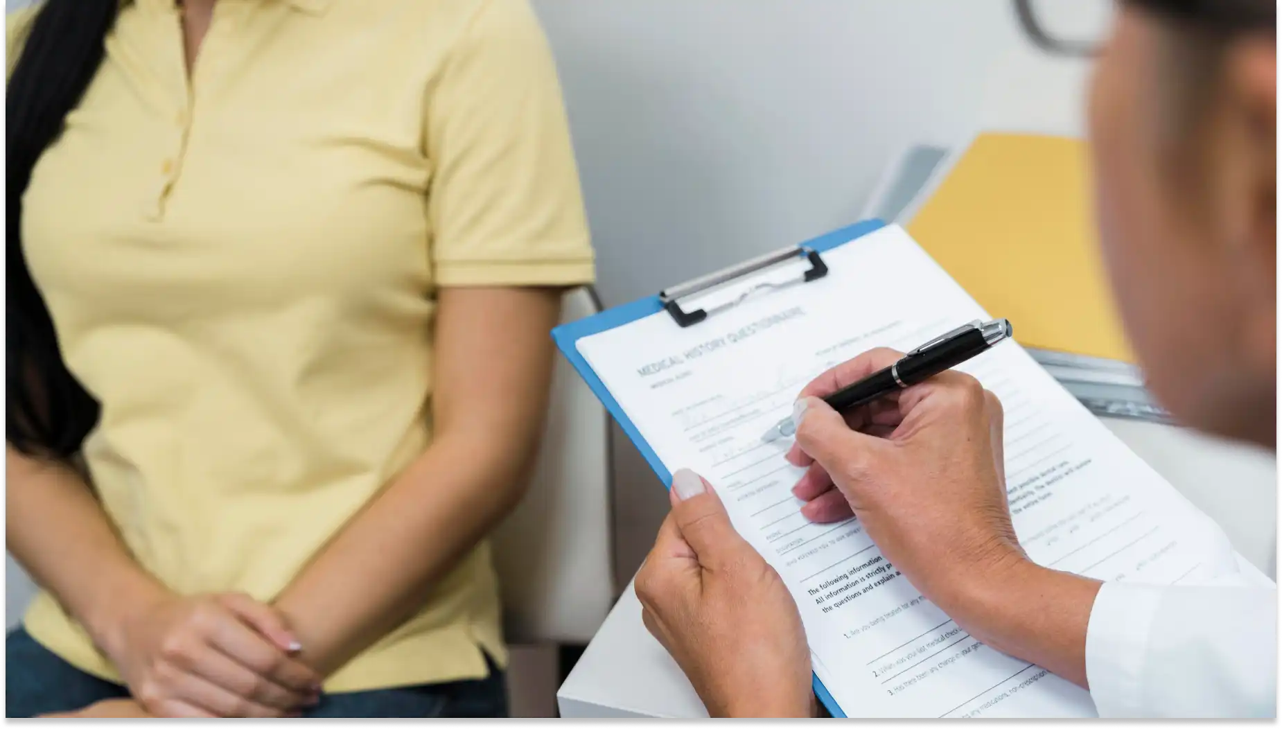 Profissional de saúde realizando preenchimento de Check-up de Bem-estar ou cadastro enquanto uma paciente observa, em ambiente clínico.