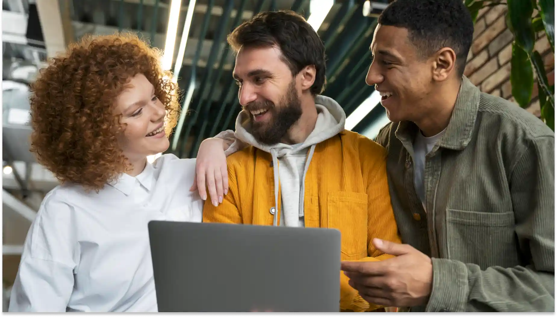 Três amigos happy usando laptop em ambiente moderno, celebrando amizade, produtividade coletiva e conexão digital, em uma cena vibrante e acolhedora.
