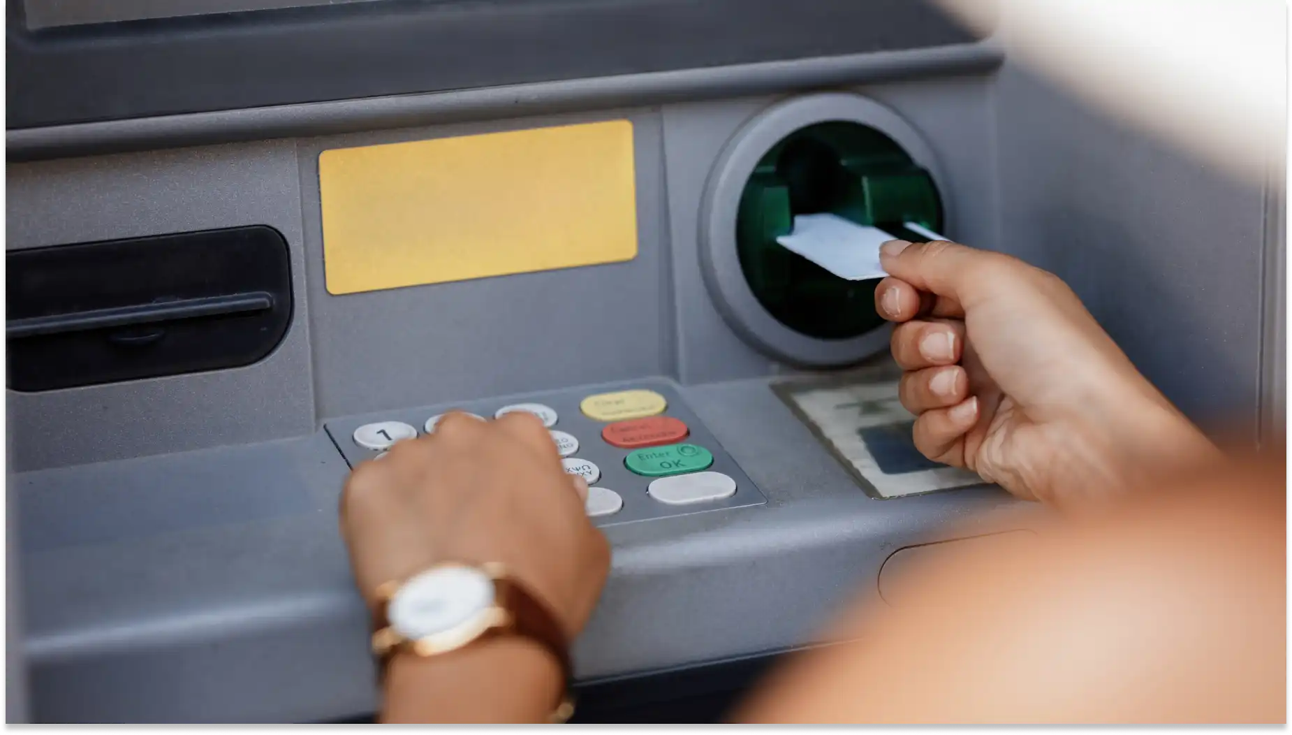 Pessoa utilizando um caixa eletrônico para fazer uma operação bancária de Saque-aniversário com cartão de débito, destacando a rotina financeira e o uso de tecnologia bancária.