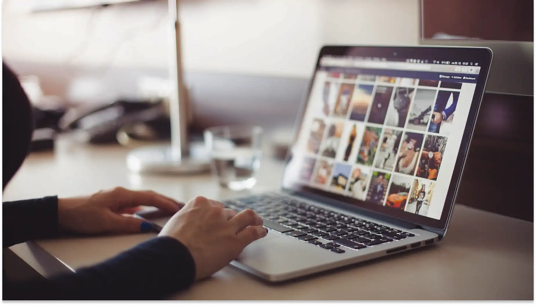 Pessoa usando um laptop com tela exibindo cursos da Escola do Trabalhador 4.0, em ambiente de escritório, com foco em dispositivos digitais e criatividade.