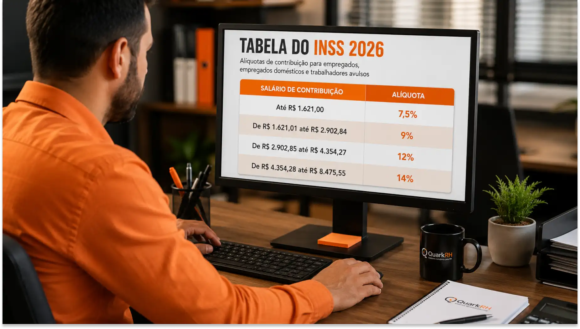 Tela de computador exibindo a Tabela do INSS 2026 com faixas de salário de contribuição e alíquotas, enquanto um homem trabalha no escritório, ao lado de caneca e caderno.
