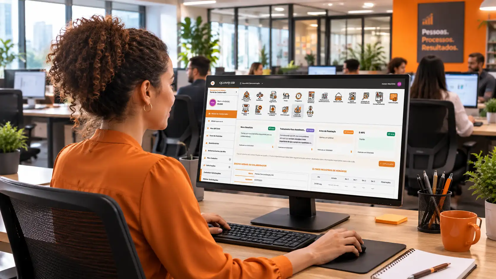 Mulher em escritório corporativo usando computador com interface de gestão de talentos e central de resultados, com tela de QuarkRH vs Sólides visível ao fundo.