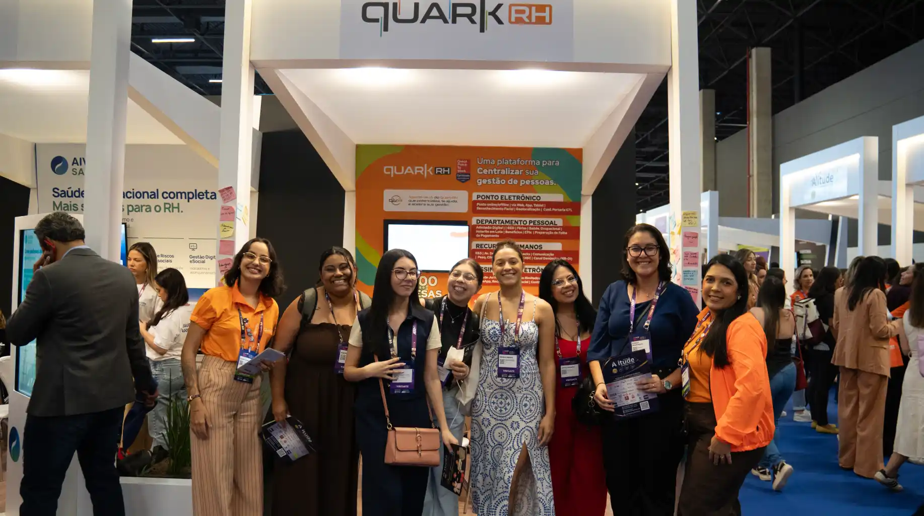 QuarkRH participa da 52ª edição do CONARH em SP: equipe em frente ao estande da QuarkRH em evento corporativo, com crachás e materiais promocionais, em ambiente de feira.