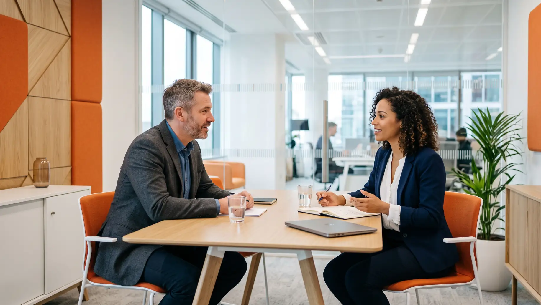 Reunião em escritório com dois profissionais conversando sentados à mesa, em ambiente corporativo moderno, representando Atraso de salário e diálogo no trabalho.